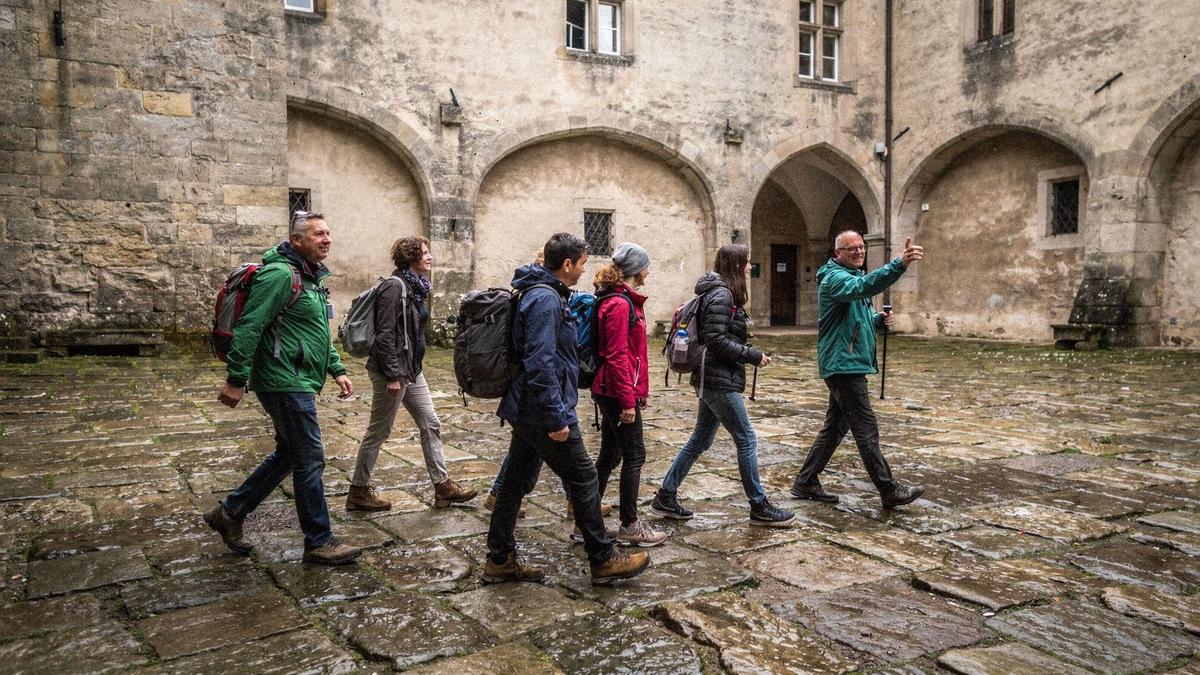 Travellers walking through the courtyard of a historic European palace on an organised city tour